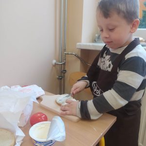 Chłopczyk smaruje kanapkę serkiem