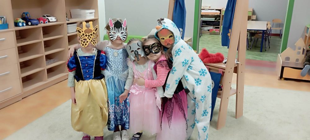 Pięć dziewczynek pozuje w kostiumach i maskach.