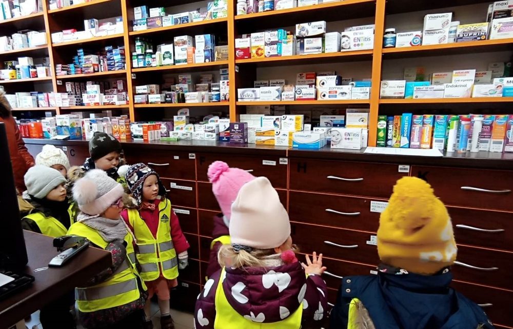 Grupa dzieci patrzy na półki z lekami.