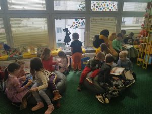 Grupa dzieci ogląda książki w bibliotece.