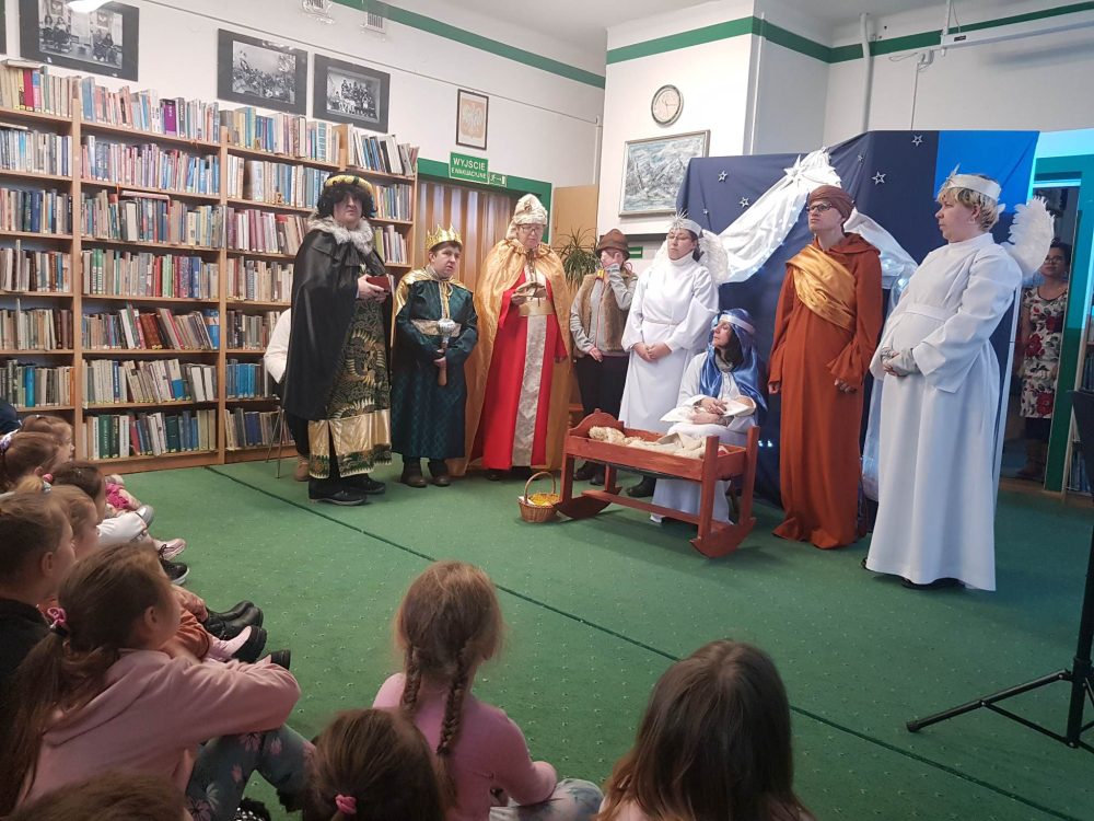Grupa przedszkolaków ogląda przedstawienie Jasełkowe. Na scenie występują aktorzy wcielający się w takie postaci jak: Maryja, Józef, dziecię, 3 Królowie i 2 Anioły.