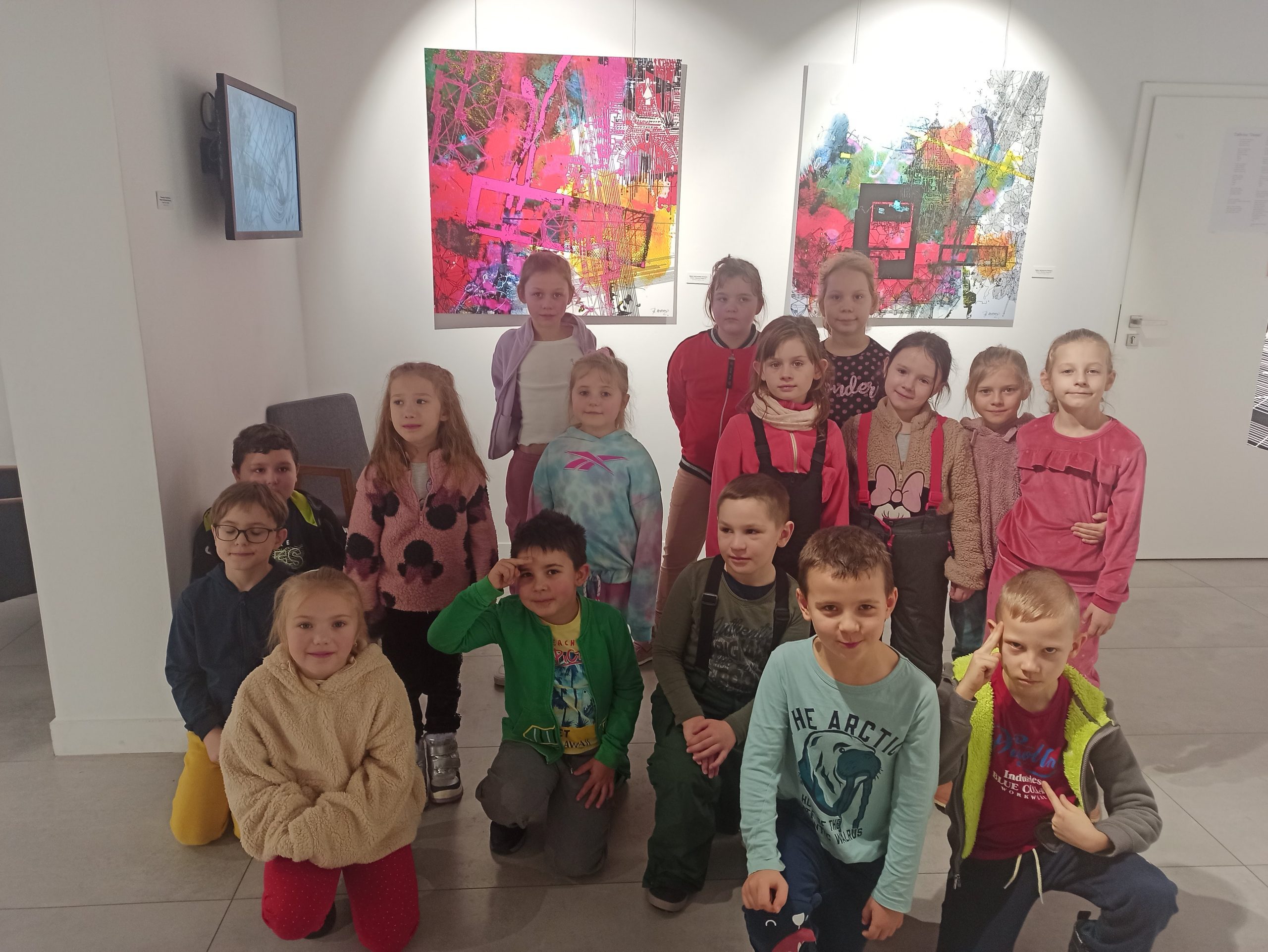 Grupa dzieci na tle prac plastycznych pani Beaty Malinowskiej-Petelenz