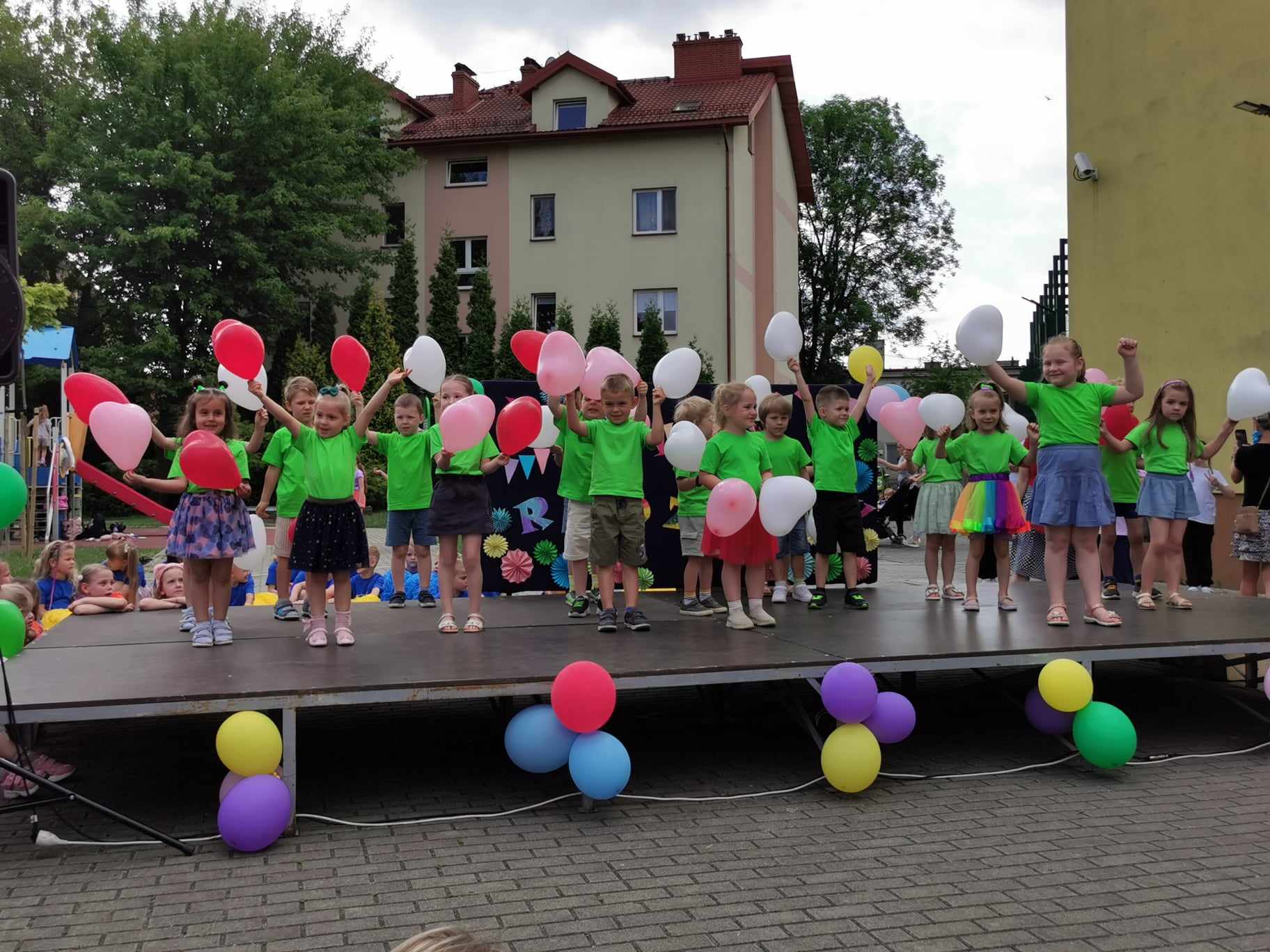 Zdjęcie nr 2 – na scenie tańczą kolorowo ubrane dzieci w wieku przedszkolnym.