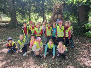 Grupa dzieci pozuje do zdjęcia z rzeźbą niedźwiedzia