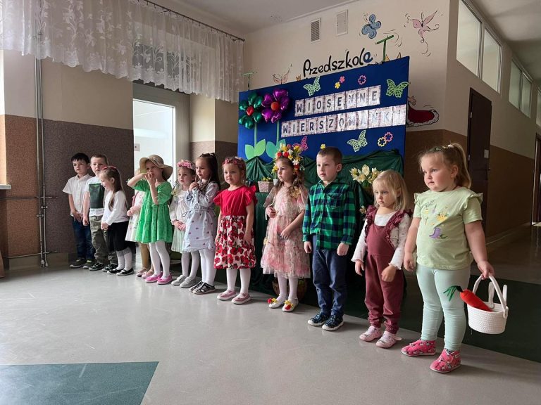 Grupa dzieci biorących udział w konkursie pozuje do zdjęcia na tle dekoracji i nazwy konkursu.