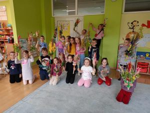 Grupa dzieci pozuje do zdjęcia. W ręku trzymają palmy.