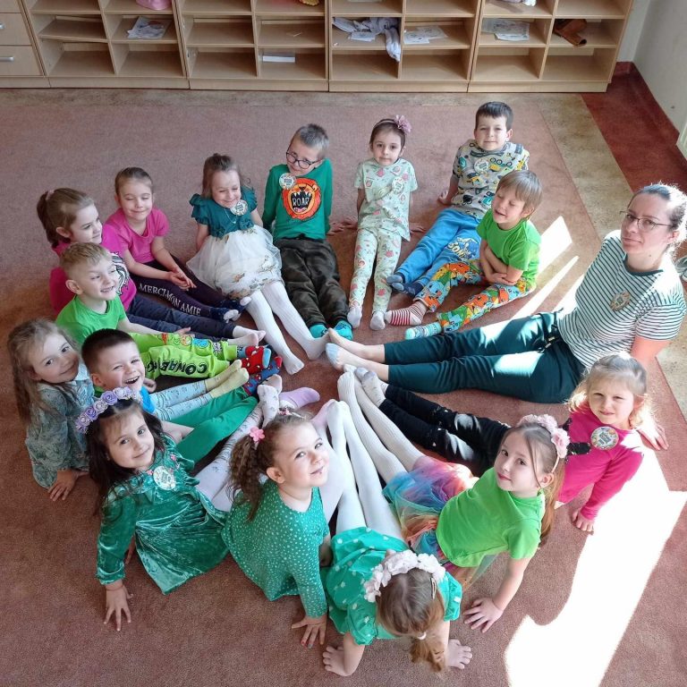 Dzieci siedzą w kole z panią z nóżkami wysuniętymi do środka. Mają na nogach różne skarpetki nie do pary.