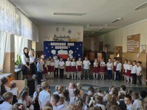 Grupa dzieci występuje podczas apelu. Na pierwszym planie widać widownie. 