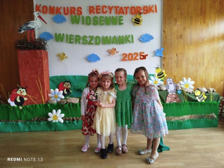 Cztery dziewczynki pozują na scenie na tle dekoracji.