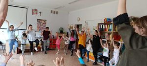 Rodzice i dzieci tańczą razem w kole.