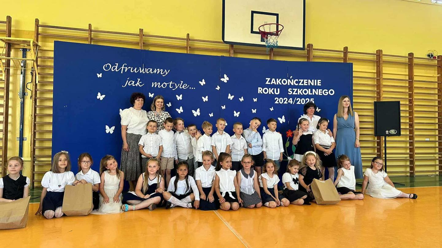 Dzieci pozują do zdjęcia wraz z paniami na tle dekoracji.