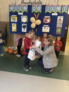 Nauczycielka wręcza nagrodę dziecku.