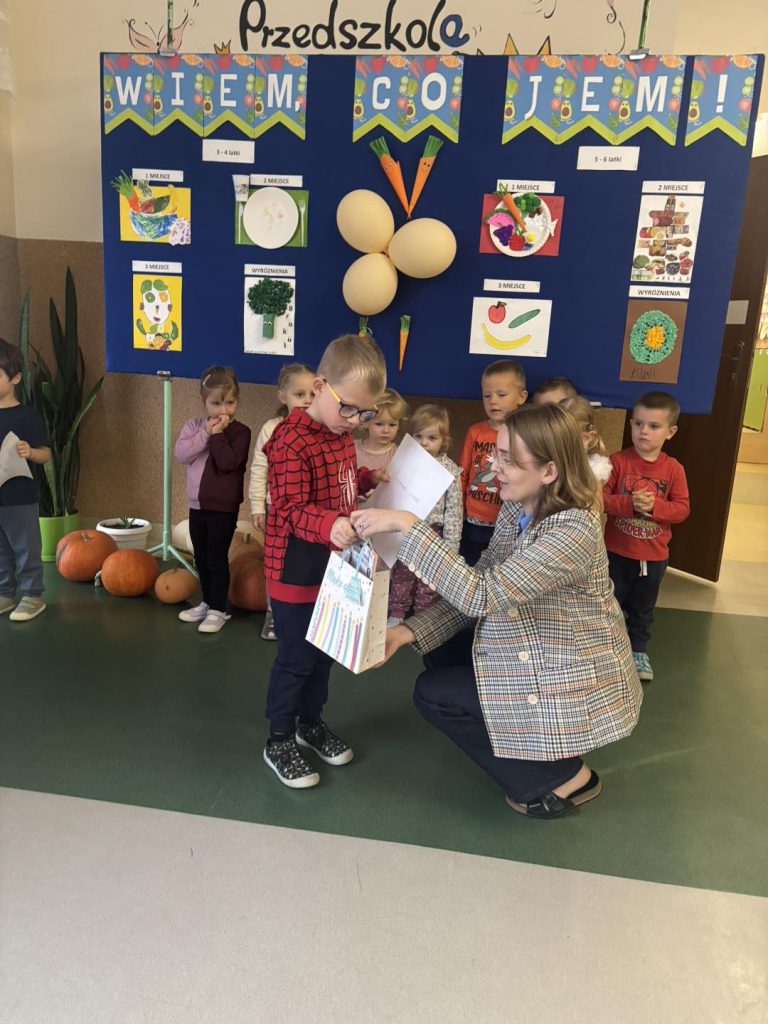 Nauczycielka wręcza nagrodę dziecku.
