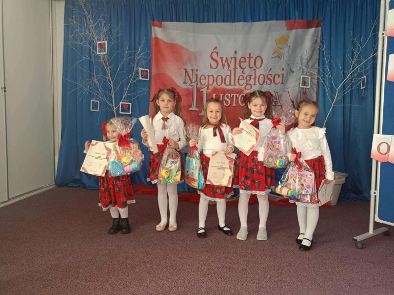 Na scenie stoją dziewczynki z dyplomami i nagrodami. W tle widać dekorację.