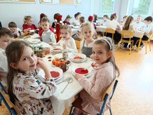 Dzieci jedzą wigilię siedzący przy stole.