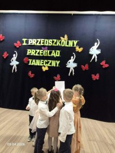 Dzieci oglądają dyplom. W tle widać dekorację i nazwę konkursu.