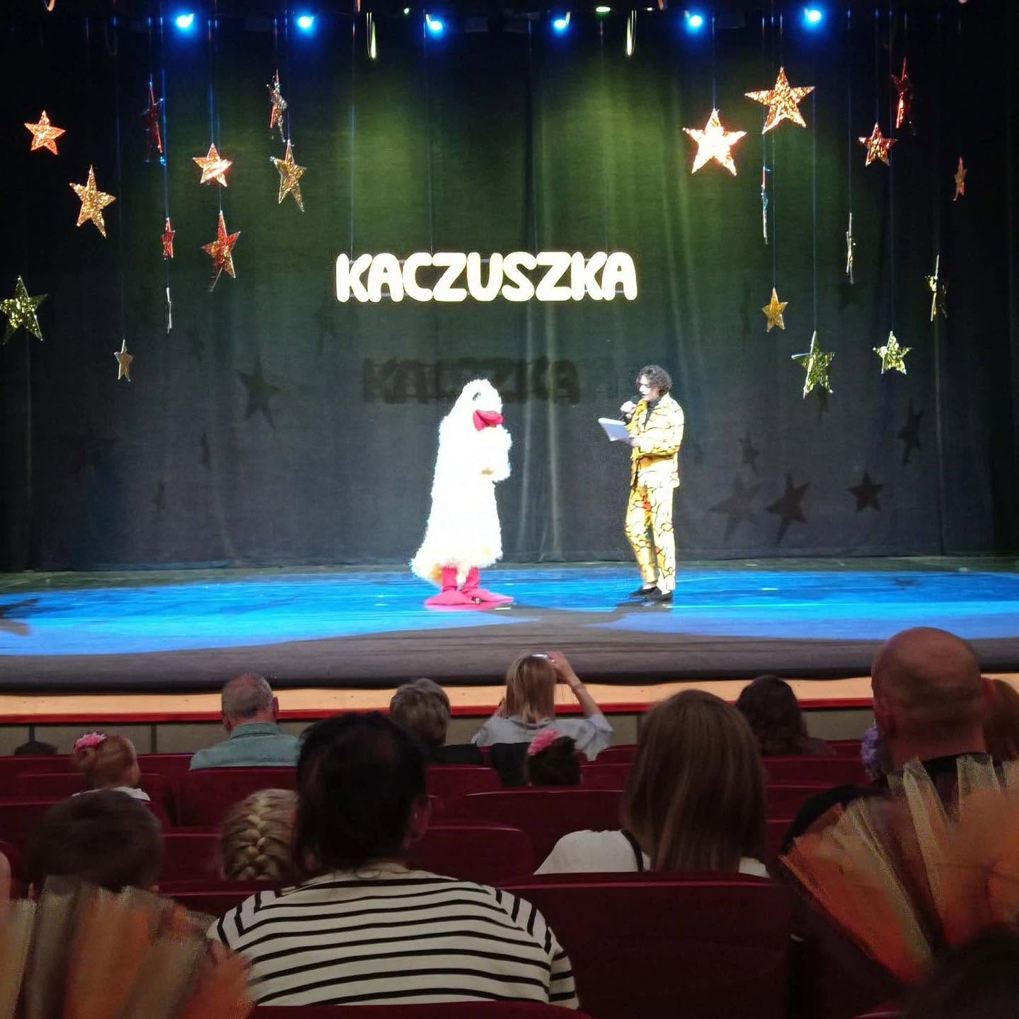 Na scenie widać postać kaczki i konferansjera.
