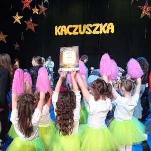 Dziewczynki pokazują dyplom. W tle widać napis "Kaczuszka"